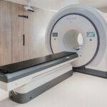 A white medical radiation therapy machine with a black patient table in a clinic