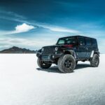 black jeep wrangler on snow covered field under blue sky during daytime
