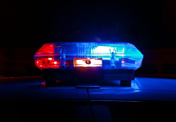 A police light bar flashing red and blue against a dark night background